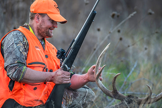 Hunter holding rifle and harvest deer antler